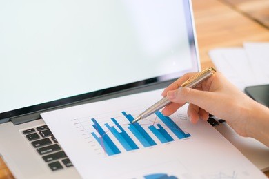 business woman hand with financial charts and laptop on the table