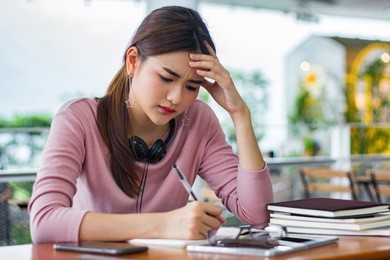 female student reading a book for the exam or doing homework.young asian college student at hard exam.
