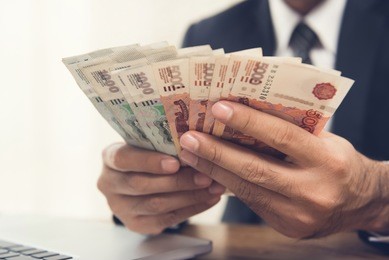 businessman counting money, russian ruble currency, at his working desk - financial, wealthy and investment concepts