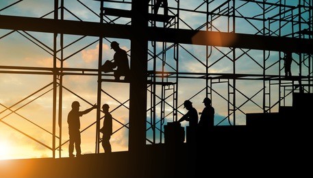 silhouette of engineer and construction team working safely on scaffolding on high rise building. over blurred background sunset pastel for industry background with light fair