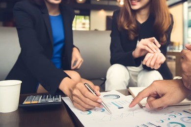 financial adviser working with clients analyzing data at the table in cafe
