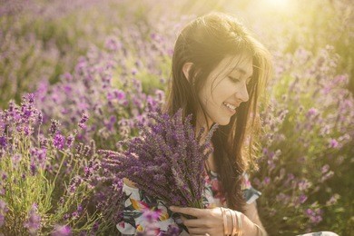 adorable romantic portrait of young woman around lavender flowers. smiling relaxed mood. summer sunset soft light. 