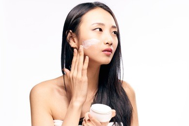 asian woman applying cosmetic cream on facial skin care face on isolated background                               