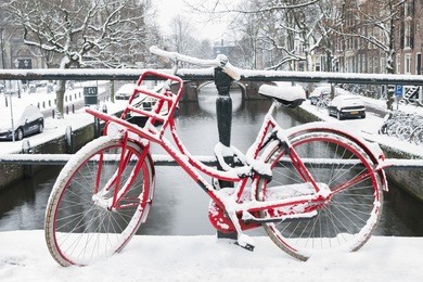 amsterdam, the netherlands. winter, red bike on a bridge and canal.