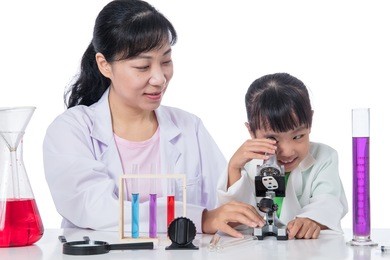 asian chinese teacher and little student girl working with microscope in isolated white background