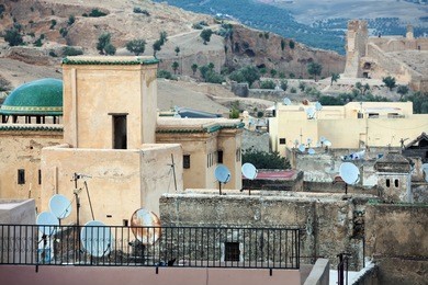 rooftops of old town with mountains in background in cloudy evening. fes el bali (medina), fez, morocco, north africa.
