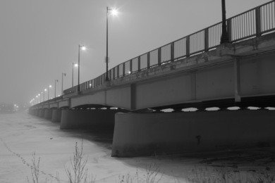 black and white photo of bridge in the fog during winter
