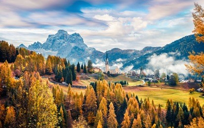 foggy autumn view of parrocchia di selva cadore church. great morning scene of dolomite alps, cortina d'ampezzo, southern alps in the veneto region of northern italy, europe.