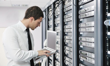 young it  engeneer business man with thin modern aluminium laptop in network server room