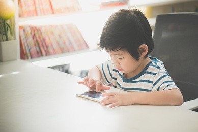 happy asian child using mobile phone on white table