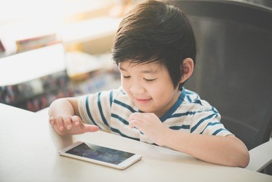 happy asian child using mobile phone on white table