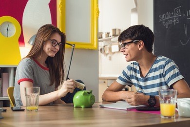 teenagers saving money in piggy bank.