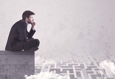 business worker sitting on concrete building edge, thinking of solving a maze concept with labyrinth and clouds