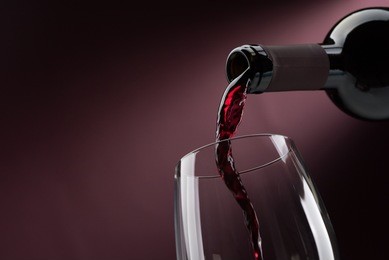pouring red wine from a bottle into a wineglass: wine tasting and celebration