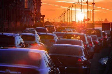 cars are in a traffic jam during a beautiful golden sunset in a big city. the movement of cars with luminous headlights on the road.