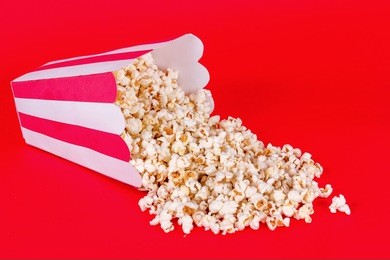spilled red and white box of popcorn on red background
