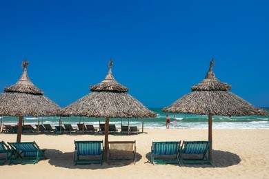 beach umbrellas and deck chairs in front of the my khe beach in da nang, vietnam.