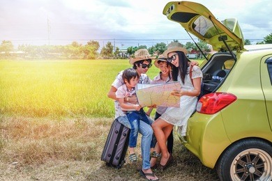family of traveler sitting near their car and using local map for searching their way.asia tourist look at the local map for find the way to go to destination.