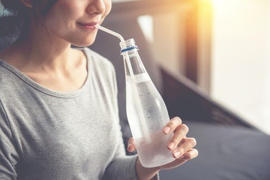 happy woman drinking cold water in morning - closeup