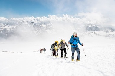 a group of mountaineers climbs to the top of a snow-capped mountain