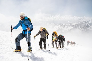 a group of mountaineers climbs to the top of a snow-capped mountain