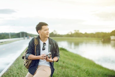 traveling asian male tourist backpackers taking photo at park.travel concept