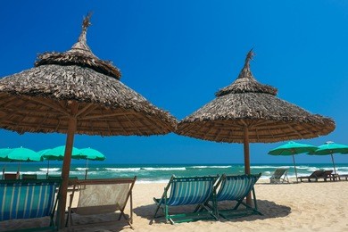 beach umbrellas and deck chairs in front of the my khe beach in da nang, vietnam.