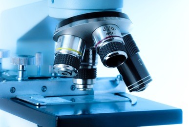 close up of microscope lenses focused on a specimen in blue light.