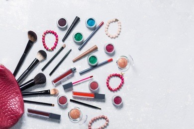a lot of bright beautiful professional cosmetics goes red purse on a white light background, brush, lipstick, shadow eyeshadow