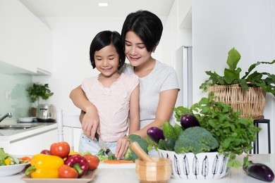 young asian mother and daughter preparing food together in the kitchen at home.