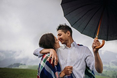 man and woman hug tender under an umbrella