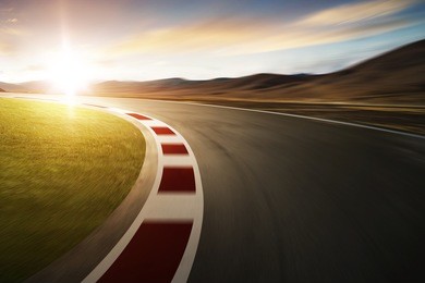 motion blurred racetrack with mountain background , sunset scene .