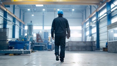 factory worker in a hard hat is walking through industrial facilities.
