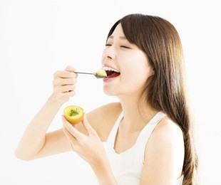happy young woman eating kiwi fruit