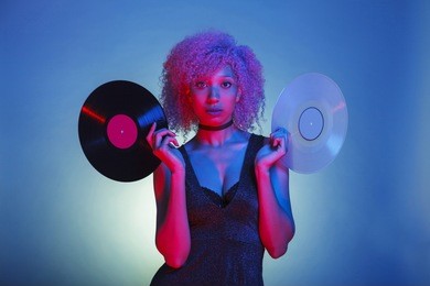 african american woman holding a pair of  music vinyls in colorful neon lights