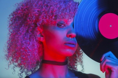 portrait of a disco woman holding a retro vinyl with eighties music and neon light