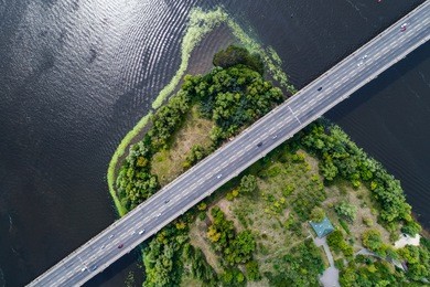 aerial view of the bridge and the road over the dnepr river over a green island in the middle of the river. kiev, ukraine