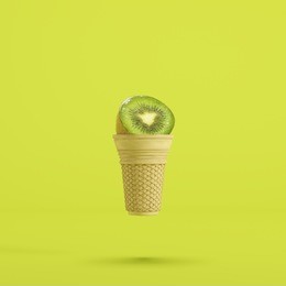 kiwi fruit with ice cream cone floating on green background, minimal fruit concept idea.