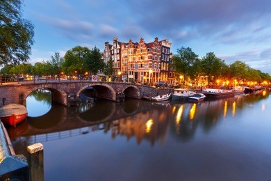 amsterdam canal, bridge and typical houses, boats and bicycles during evening twilight blue hour, holland, netherlands. used toning