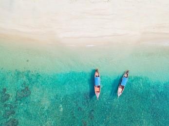 beach top view or aerial view with two long tail boat on emerald water
