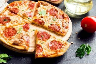pepperoni pizza - fresh homemade pizza with pepperoni, cheese and tomato sauce on rustic black stone background wirh copy space.