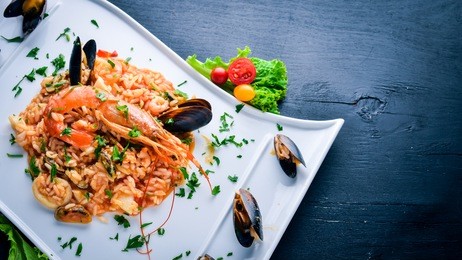 risotto with seafood and royal shrimp. on a wooden background. top view. free space for text.