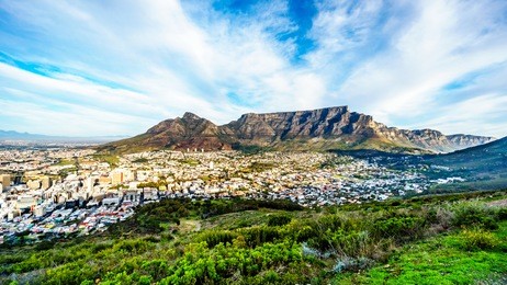 sun setting over cape town, table mountain, devils peak, lions head and the twelve apostles. viewed from the road to signal hill at cape town, south africa