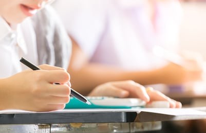 soft focus.high school or university student holding pencil writing on paper answer sheet.sitting on lecture chair doing final exam attending in examination room or classroom.student in uniform.
