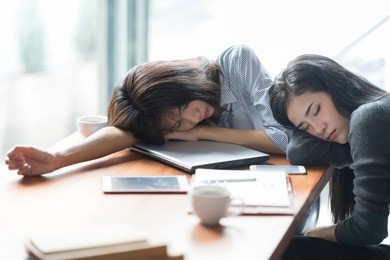 tired and sleepy business woman closing eyes laying on laptop.overtime hours concept.