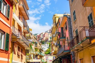 view of the colorful houses along the main street in a sunny day in manarola. manarola is one of the five famous cinque terre villages in natiolal park. liguria, italy, europe