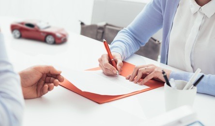 woman signing a car insurance policy, the agent is holding the document