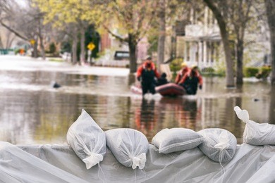 flood protection sandbags with flooded homes in the background (montage)