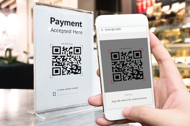 qr code payment , online shopping , cashless technology concept. coffee shop accepted digital pay without money , plastic tag on table and hand using mobile phone application to scan qr code.