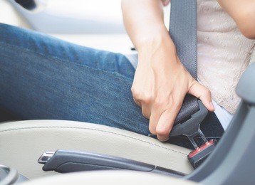 closeup woman hand sitting inside car fastening seat belt. safety belt safety first.